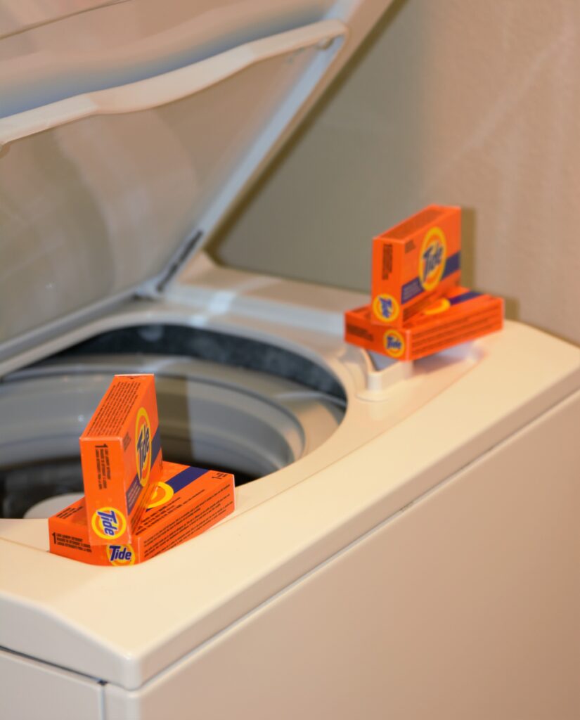 An open washing machine with packets of laundry detergent on top