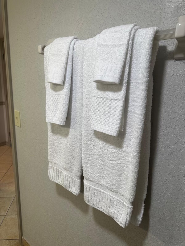 Neatly hung white bath towels in a hotel bathroom